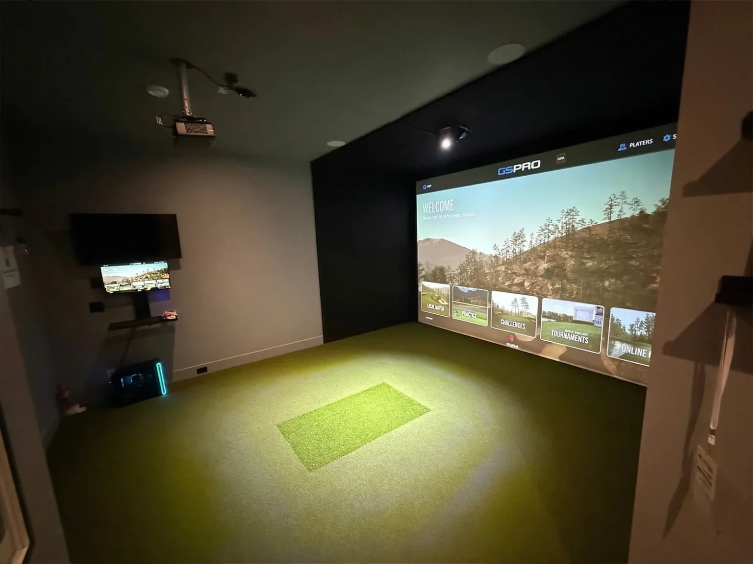 Custom golf simulator room in Calgary with wall-to-wall screen, Precision Putt turf and ceiling-mounted projector